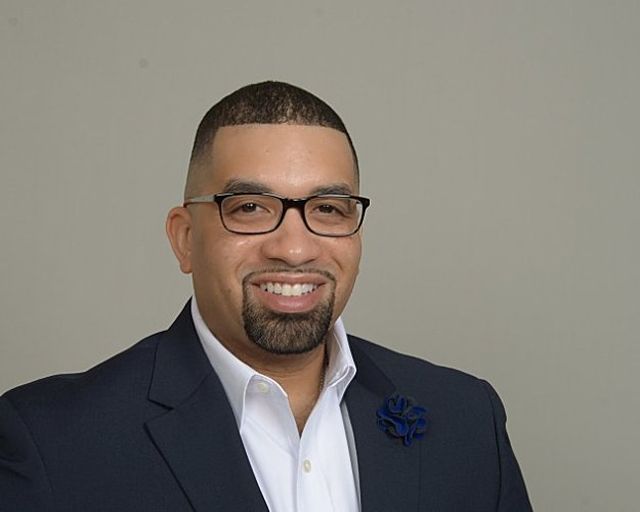 Romar Steed in a navy suit with a blue pocket square.